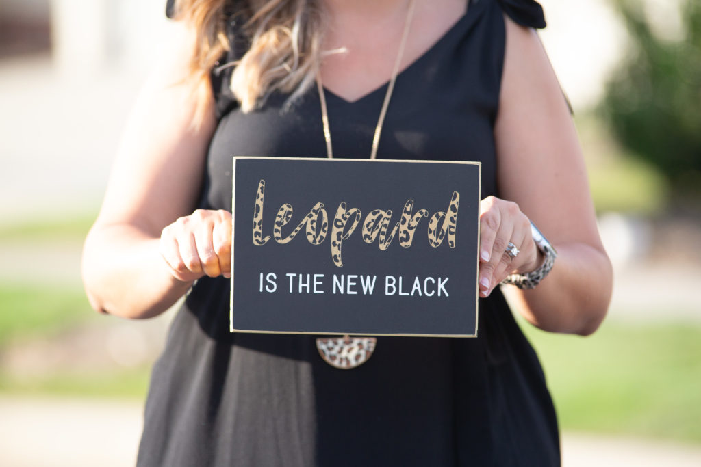 Woman holding sign that reads "leopard is the new black" https://jamiesellsraleigh.com 
what to wear for branding photos